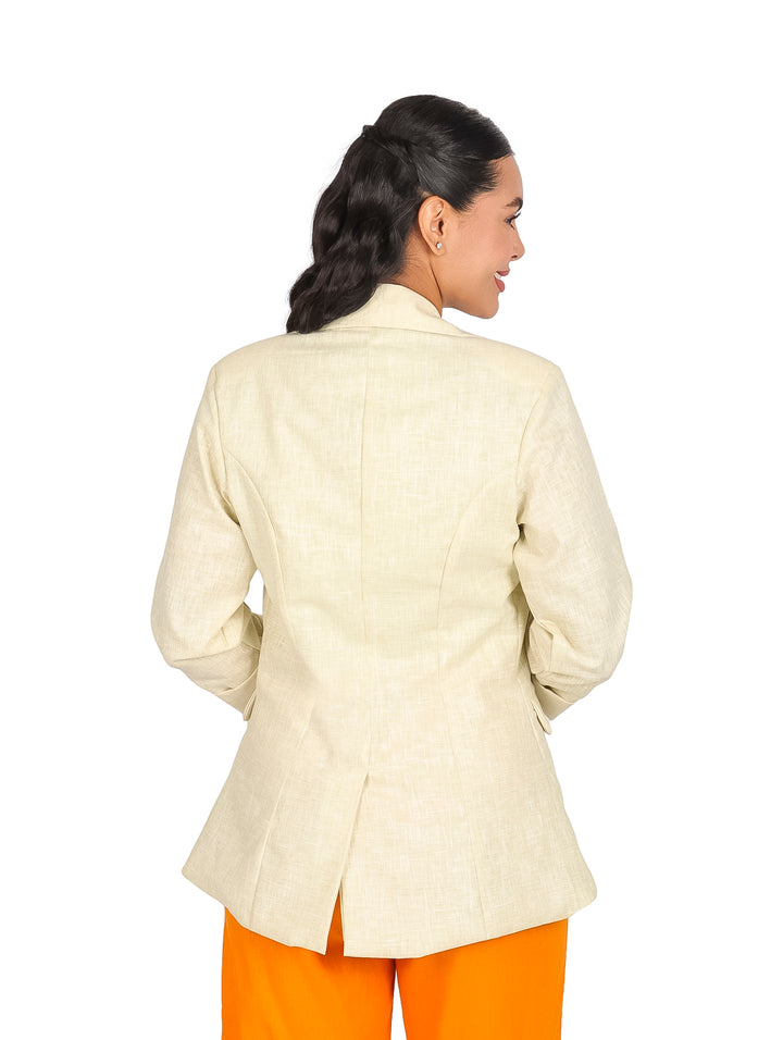 Mujer vistiendo un saco de lino color beige con botones y pantalones naranjas.