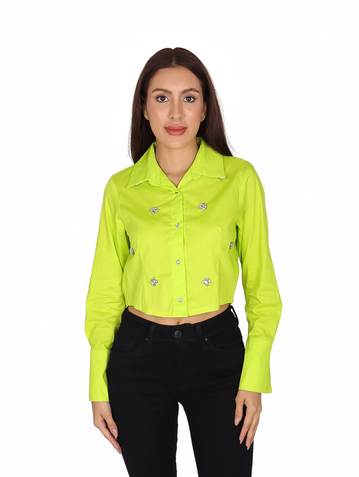 Mujer vistiendo una camisa corta de color lima con detalles de piedras brillantes y manga larga.