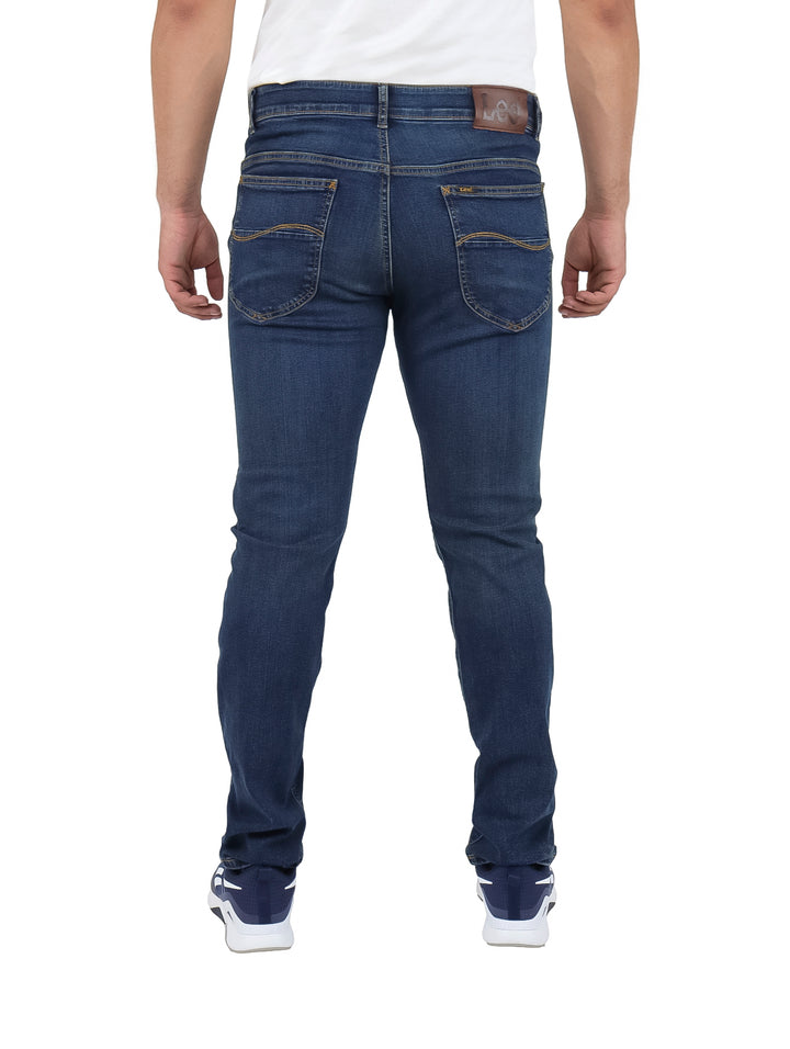 Hombre vistiendo pantalones jeans slim fit de mezclilla color azul marino.
