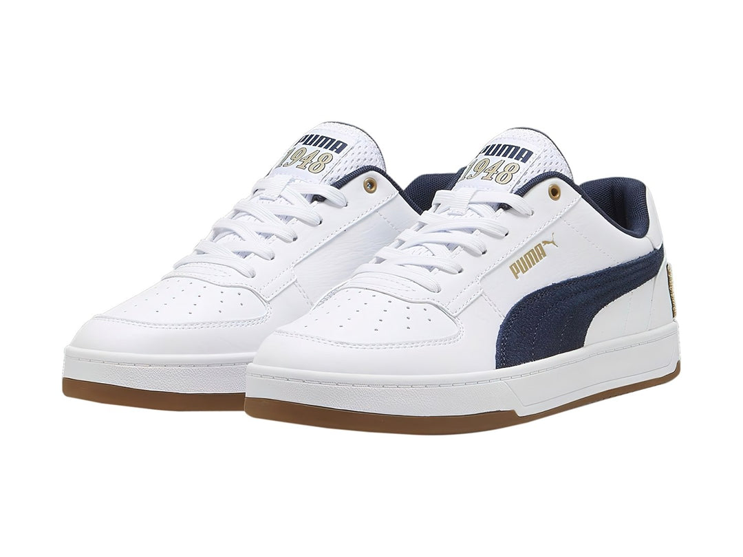 Tenis PUMA blancos con franja azul marino y suela color café.