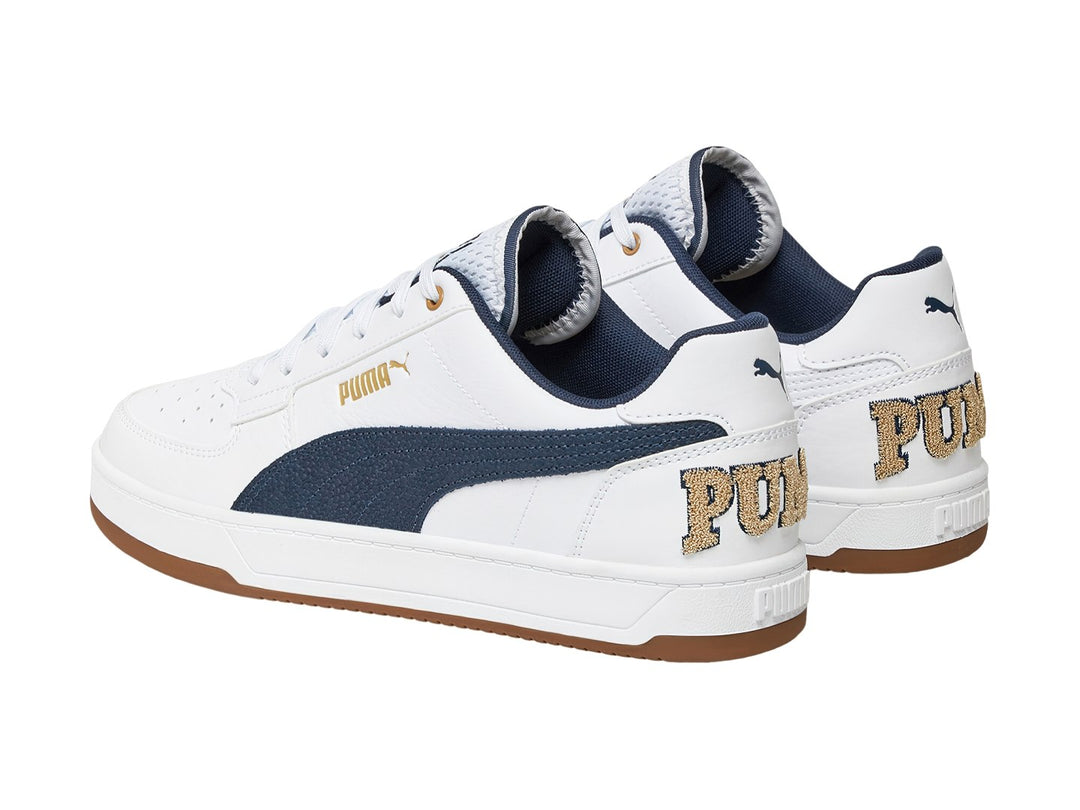 Tenis PUMA blancos con franja azul marino y suela color café.