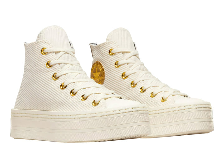 Tenis Converse color crema con suela de plataforma y detalles dorados en el logo y ojillos.