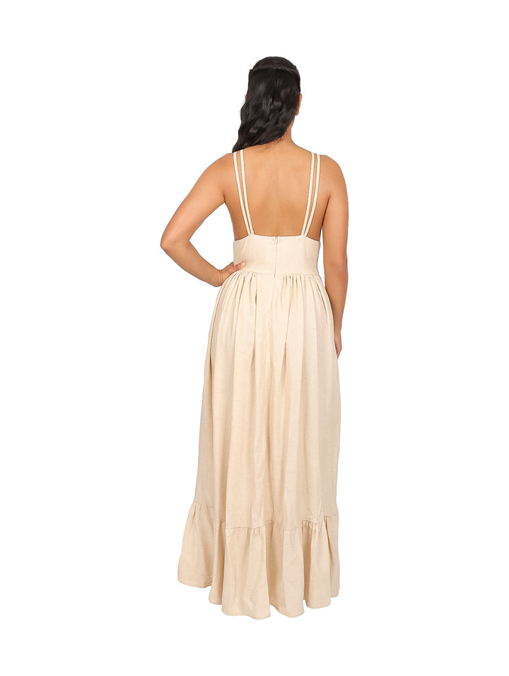 Mujer vistiendo un vestido largo de lino en color natural con escote en V y tirantes.