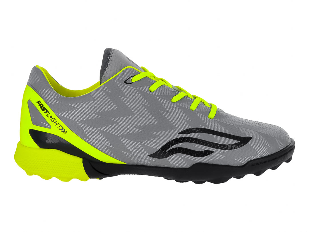 Zapato de fútbol Furia para niños en color gris con detalles en amarillo neón y suela negra para césped sintético.