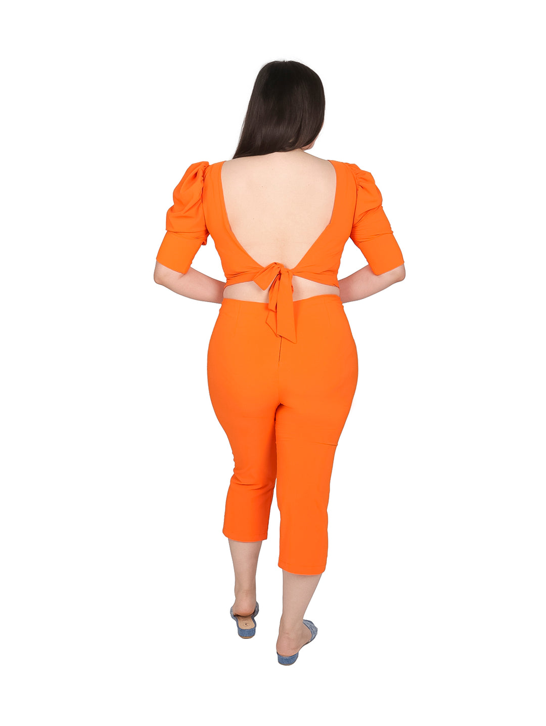 Mujer vistiendo un conjunto color naranja compuesto por blusa corta y pantalón capri.