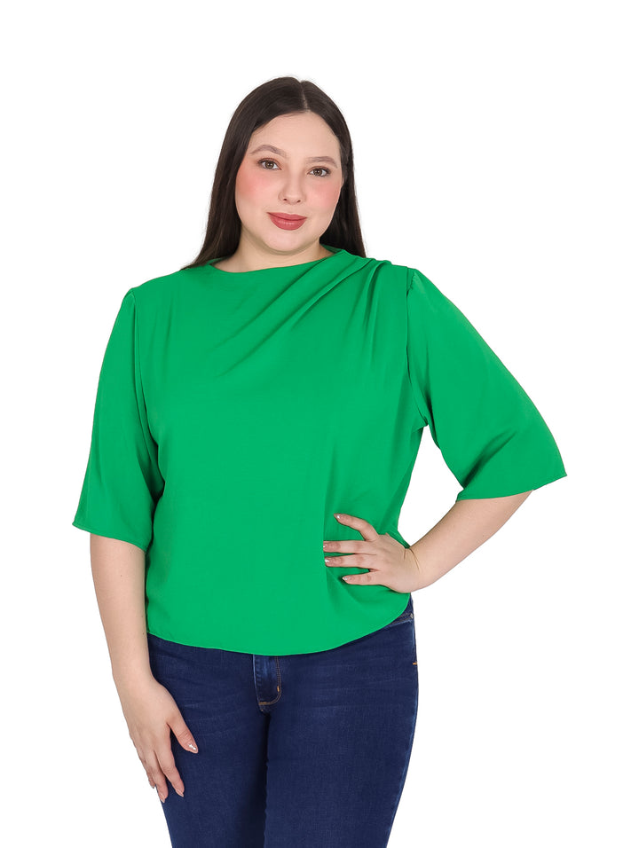 Mujer vistiendo blusa verde de manga 3/4 con detalle drapeado en el cuello y pantalones jeans azules.