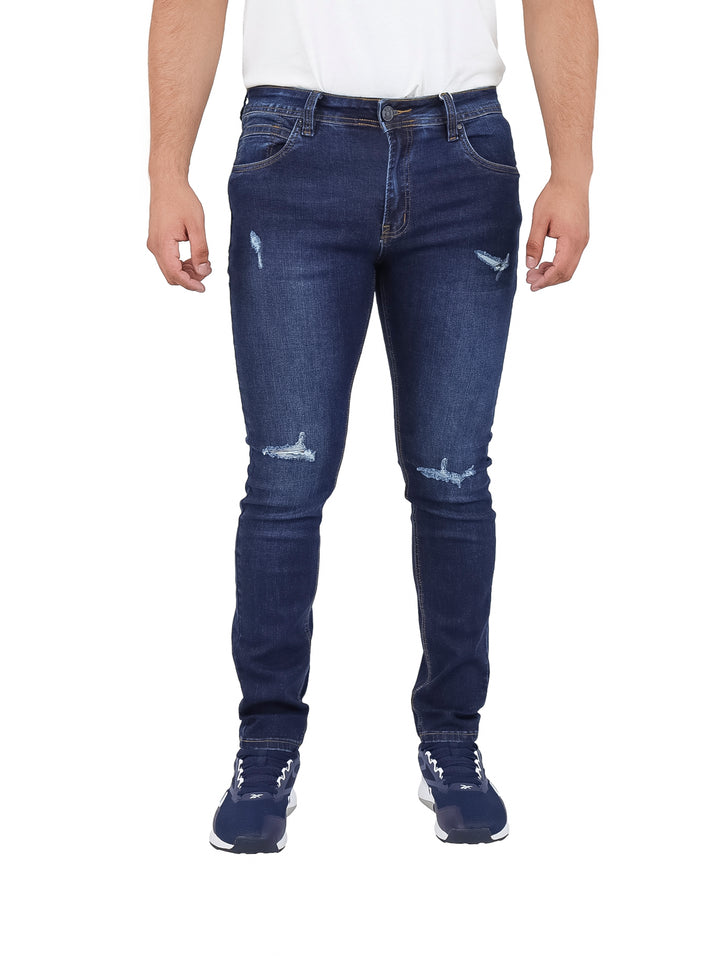 Hombre vistiendo pantalones jeans azul marino con detalles desgastados.