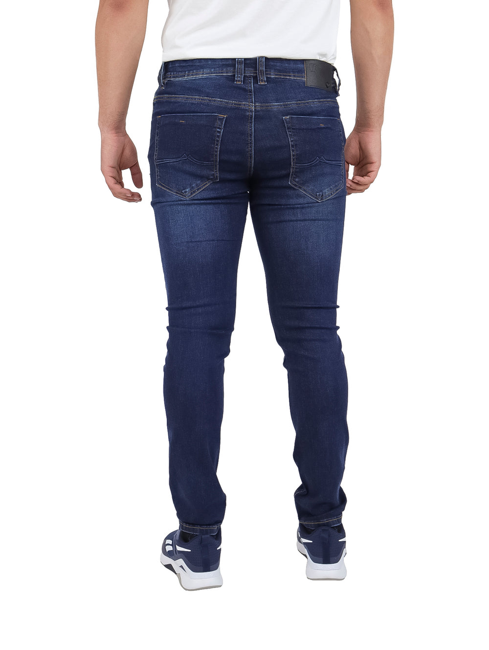 Hombre vistiendo pantalones jeans azul marino con detalles desgastados.