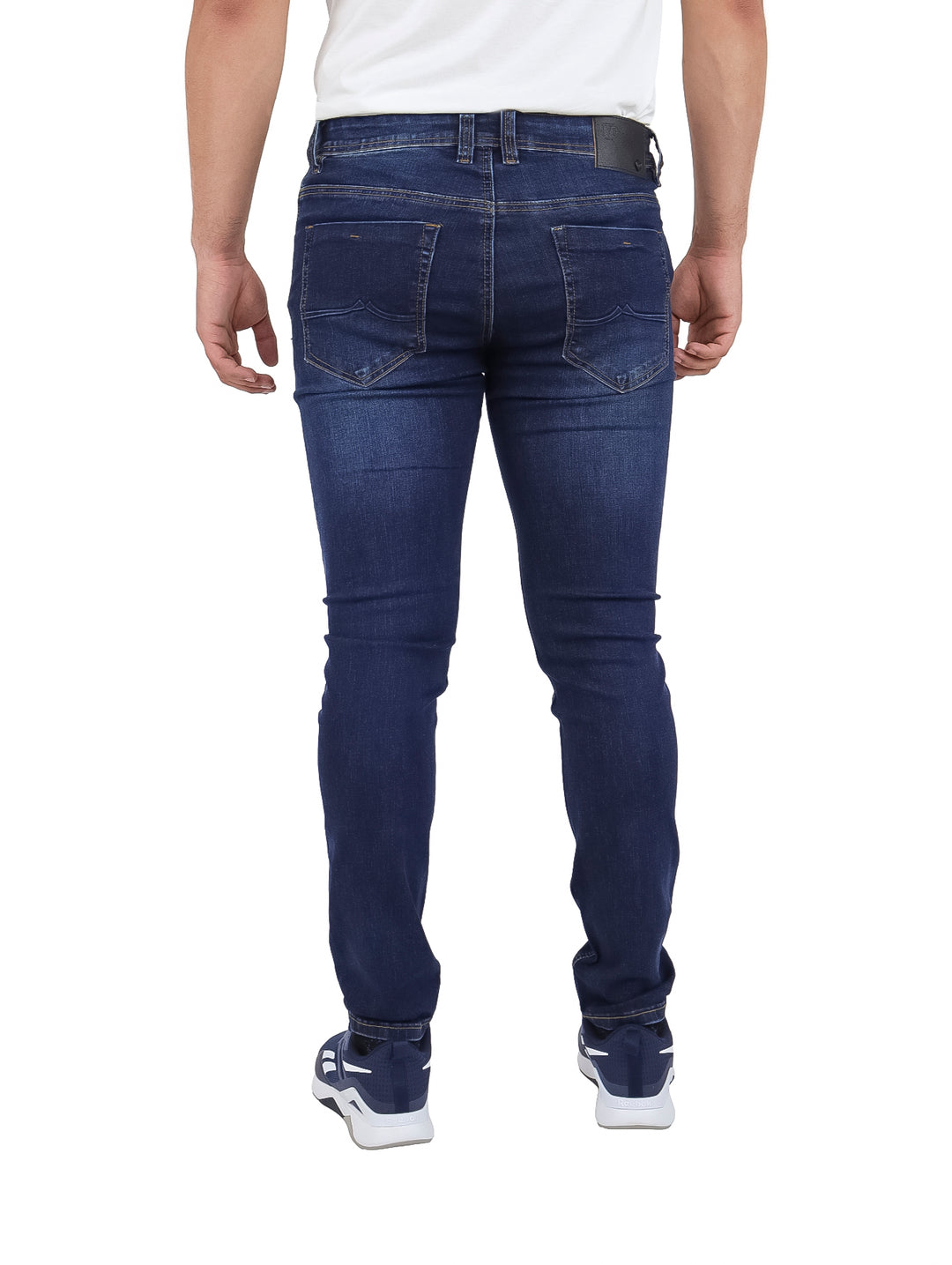 Hombre vistiendo pantalones jeans azul marino con detalles desgastados.