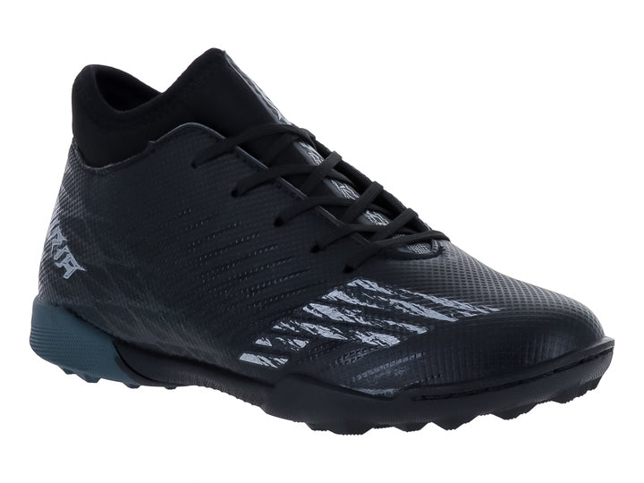 Zapato de fútbol Furia para niño en color negro con detalles en gris oxford y suela para césped sintético.