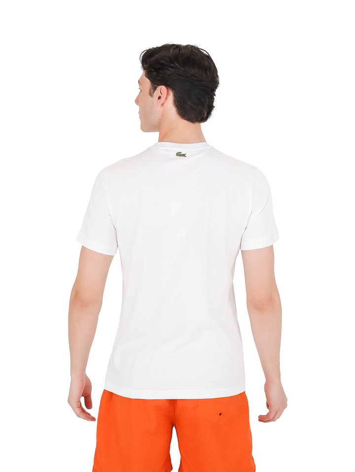 Hombre con camiseta blanca de manga corta Lacoste con logotipo verde en el pecho.