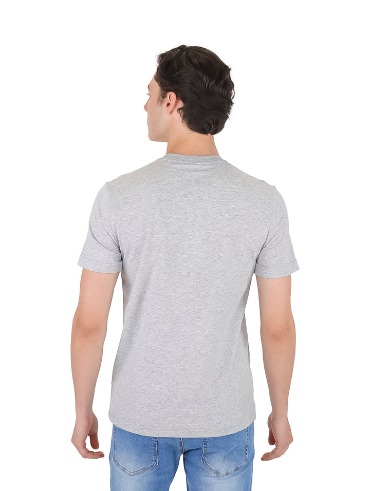 Hombre vistiendo una camiseta gris de manga corta con el logotipo de Lacoste en el pecho.