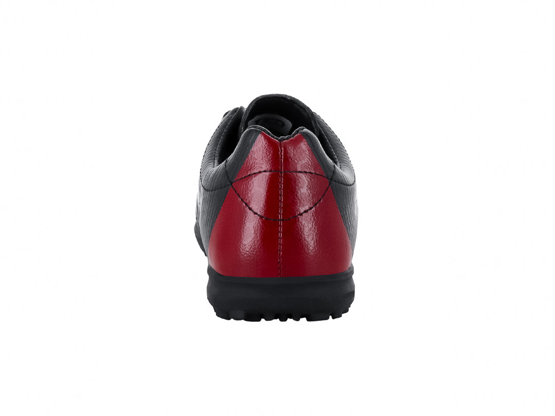 Zapato de fútbol Leon Trucco color negro con detalle rojo en el talón y suela para césped sintético.