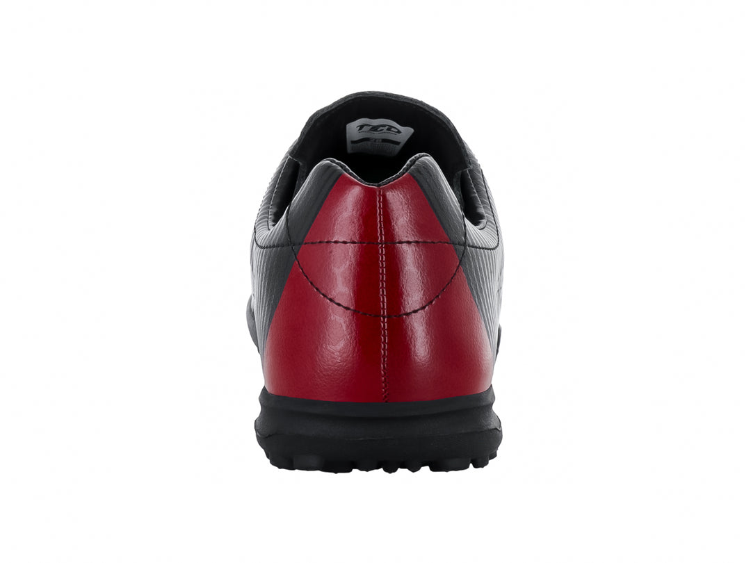 Zapato de fútbol Leon Trucco color negro con detalle rojo en el talón y suela para césped sintético.