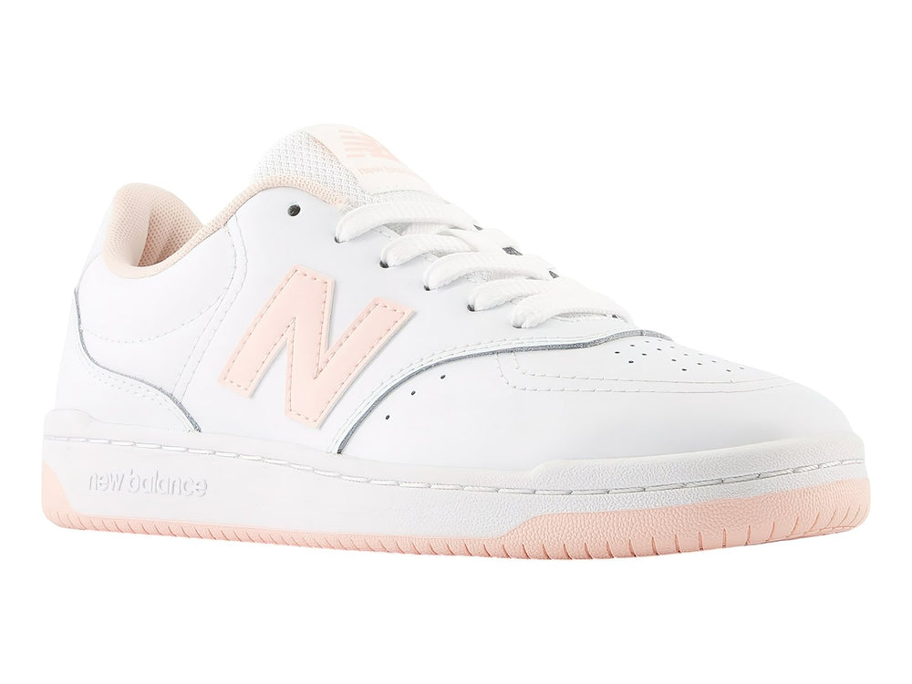 Tenis New Balance blancos con detalles en rosa y suela rosa claro para niña.