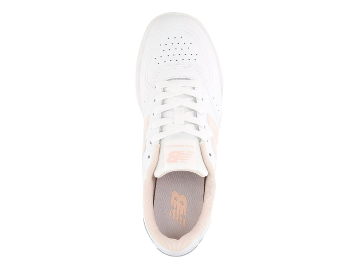 Tenis New Balance blancos con detalles en rosa y suela rosa claro para niña.