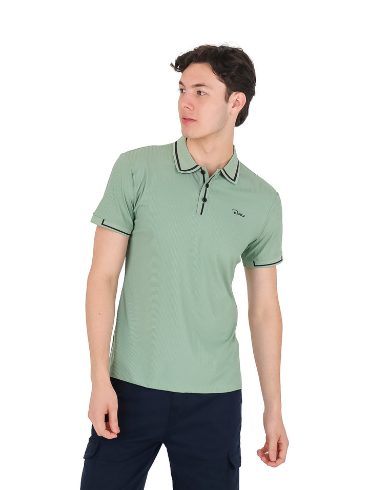 Hombre vistiendo playera polo color verde con detalles en negro en el cuello y mangas.