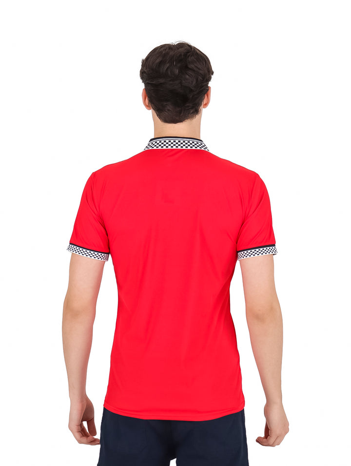Hombre vistiendo playera polo roja con cuello y puños en patrón de cuadros blancos y negros y cierre frontal.