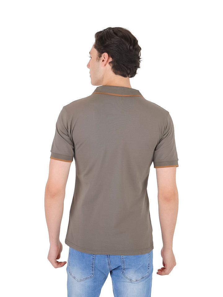 Hombre vistiendo playera polo color gris con detalles en marrón en el cuello y mangas.