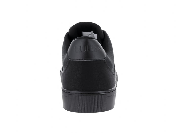 Tenis negros GUESS de corte bajo con suela plana y detalles texturizados.