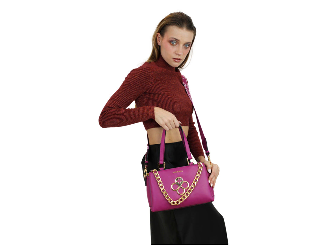 Bolso de mano color fucsia con detalles y cadena decorativa en color dorado y asa superior.