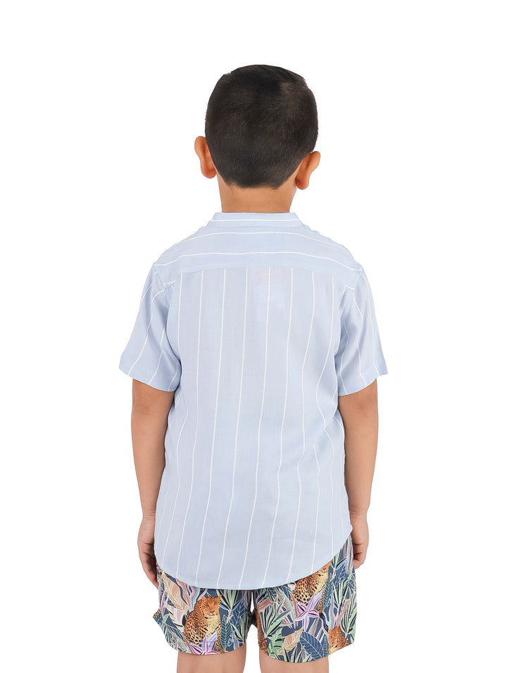 Niño vistiendo camisa de manga corta color azul acero con rayas blancas verticales.
