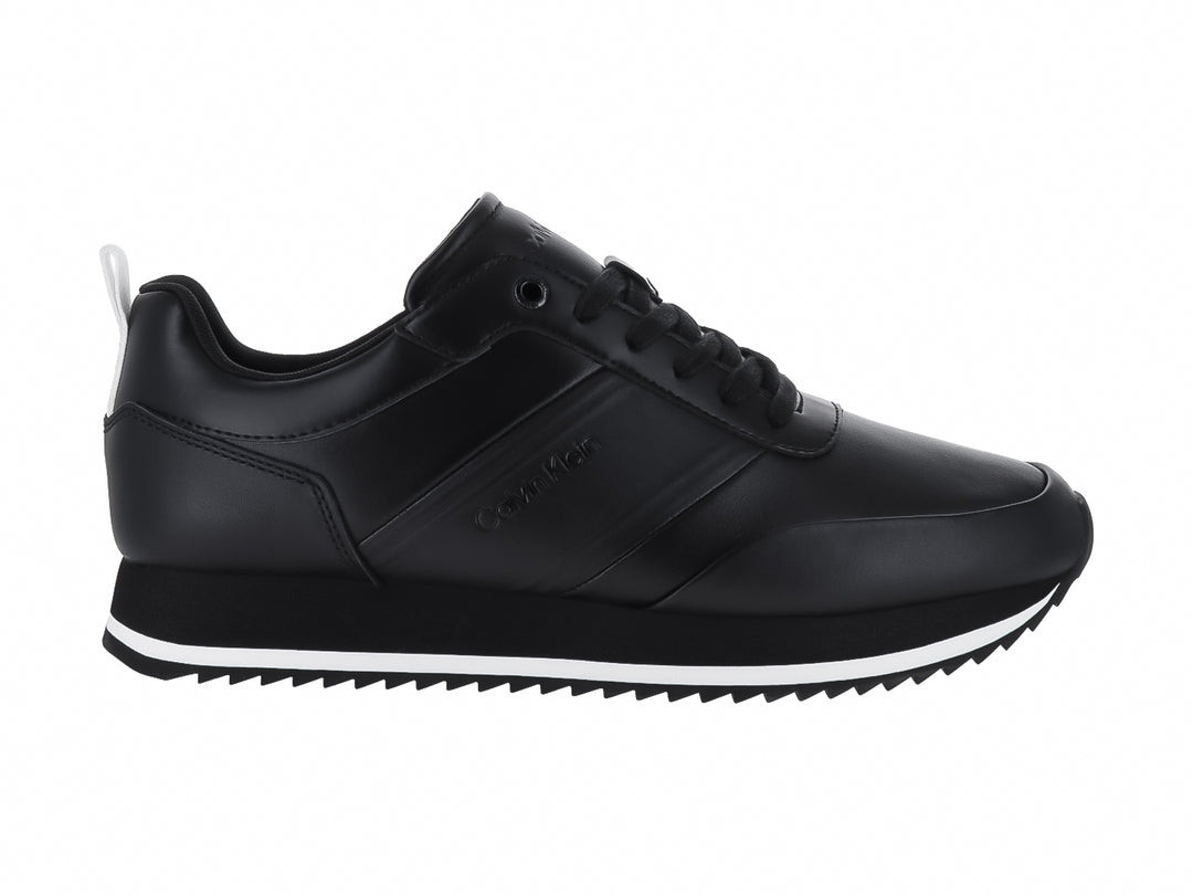 Tenis negros de cuero Calvin Klein con suela blanca dentada y cordones negros.