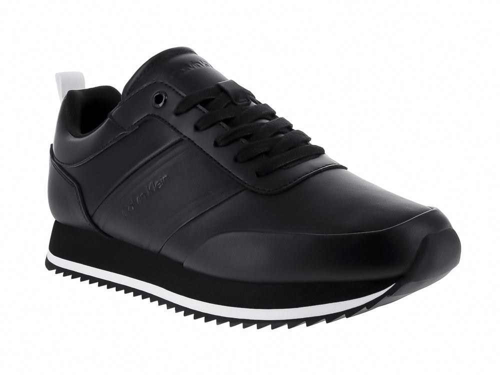 Tenis negros de cuero Calvin Klein con suela blanca dentada y cordones negros.