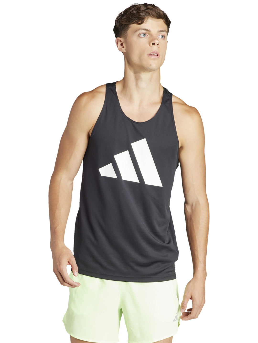 Hombre usando camiseta sin mangas Adidas negra con logo blanco y shorts deportivos verde claro.