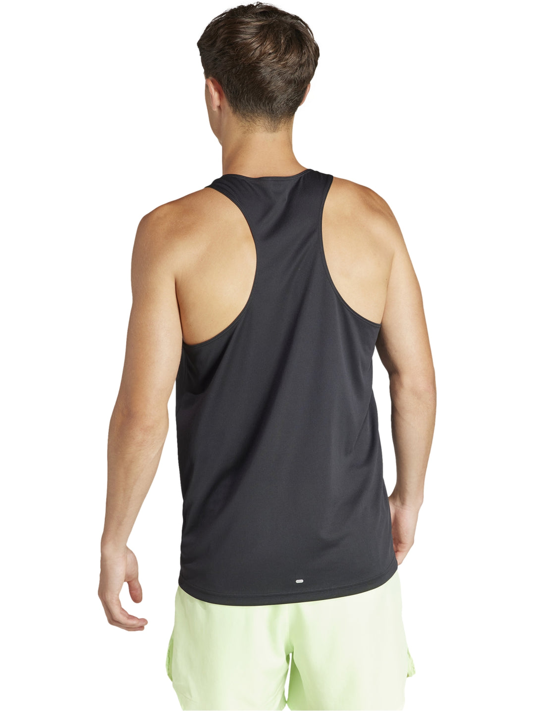 Hombre usando camiseta sin mangas Adidas negra con logo blanco y shorts deportivos verde claro.