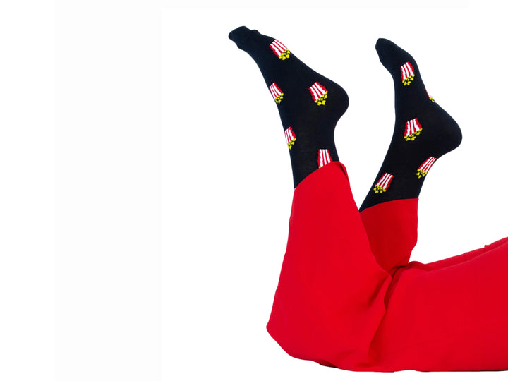 Par de calcetines negros con estampado de palomitas de maíz en colores rojo, blanco y amarillo.