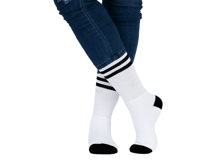 Par de calcetines deportivos blancos con rayas negras superiores y detalles en negro en talón y punta.