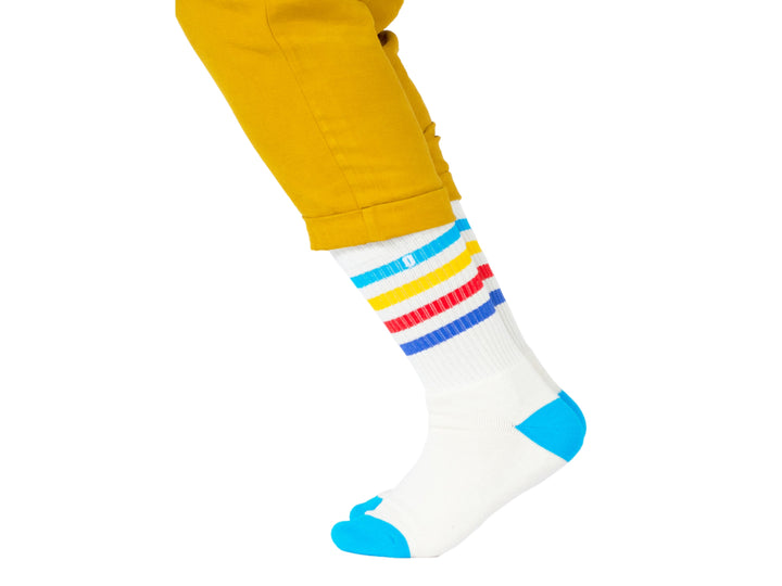 Par de calcetines blancos con rayas horizontales en azul, amarillo y rojo, y puntas azules.