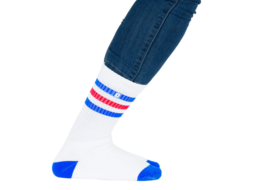 Par de calcetines blancos con rayas azules y rojas en la parte superior y punta azul.
