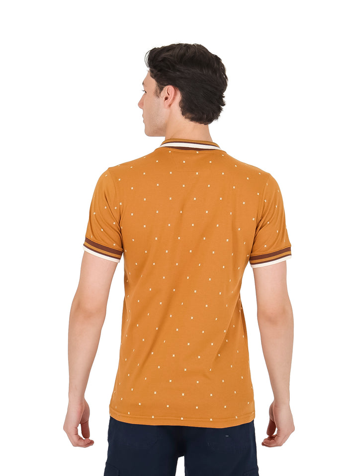 Hombre vistiendo playera polo color ocre con estampado de pequeños puntos blancos y detalles contrastantes en el cuello.