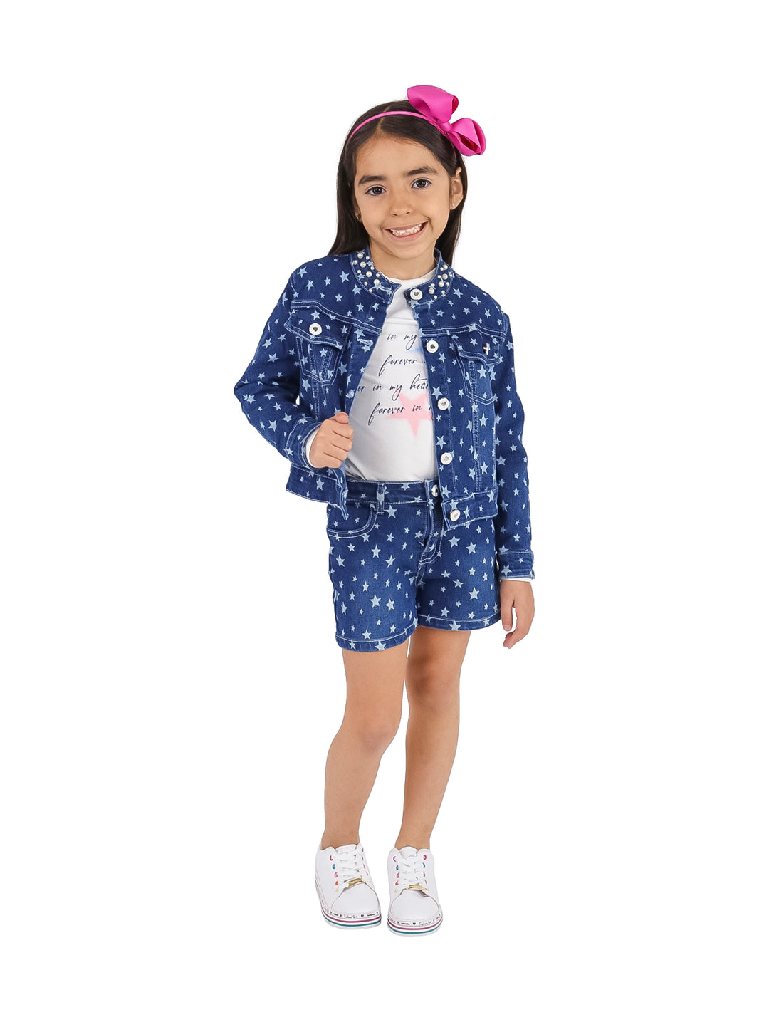 Niña vistiendo conjunto de chaqueta y short azul con estampado de estrellas blancas y camiseta blanca.