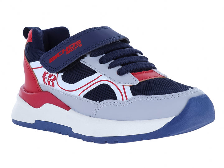 Zapato deportivo infantil marca BICHOS en colores azul marino, gris y rojo con suela blanca y cierre de velcro.