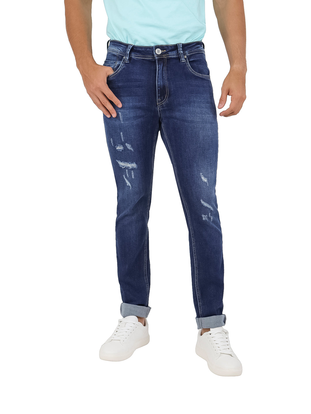 Hombre vistiendo pantalones jeans de mezclilla azul oscuro con detalles desgastados y tenis blancos.