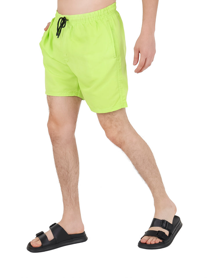 Hombre vistiendo un traje de baño corto color verde neón con cordón negro en la cintura.
