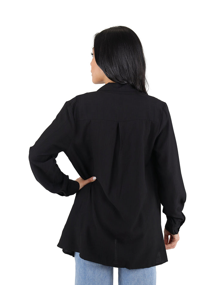 Mujer vistiendo conjunto de camisa negra de manga larga abierta y top corto negro.