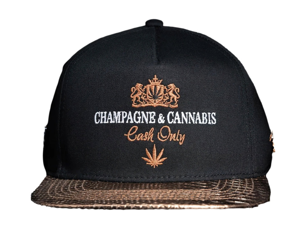 Gorra snapback color negro con visera dorada y bordados frontales de Champagne & Cannabis Cash Only.