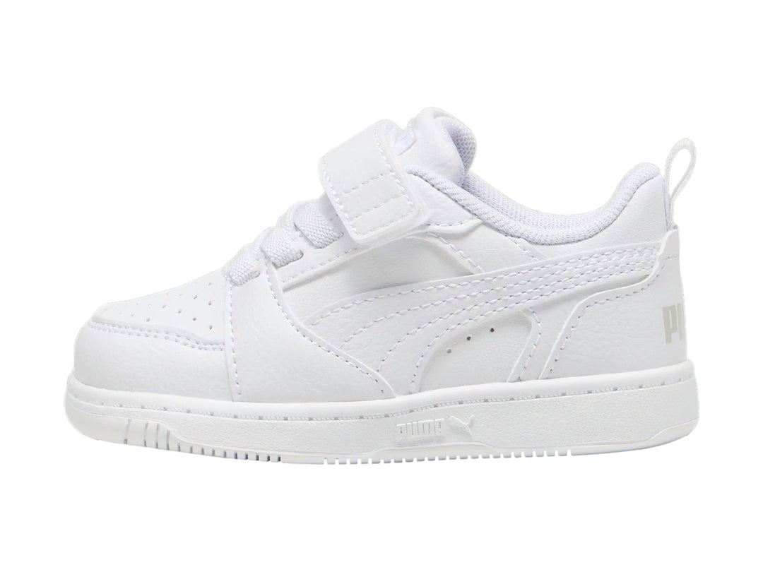 Tenis PUMA Rebound V6 Lo AC+PS en color blanco con detalles en gris claro y cierre de velcro para niños.