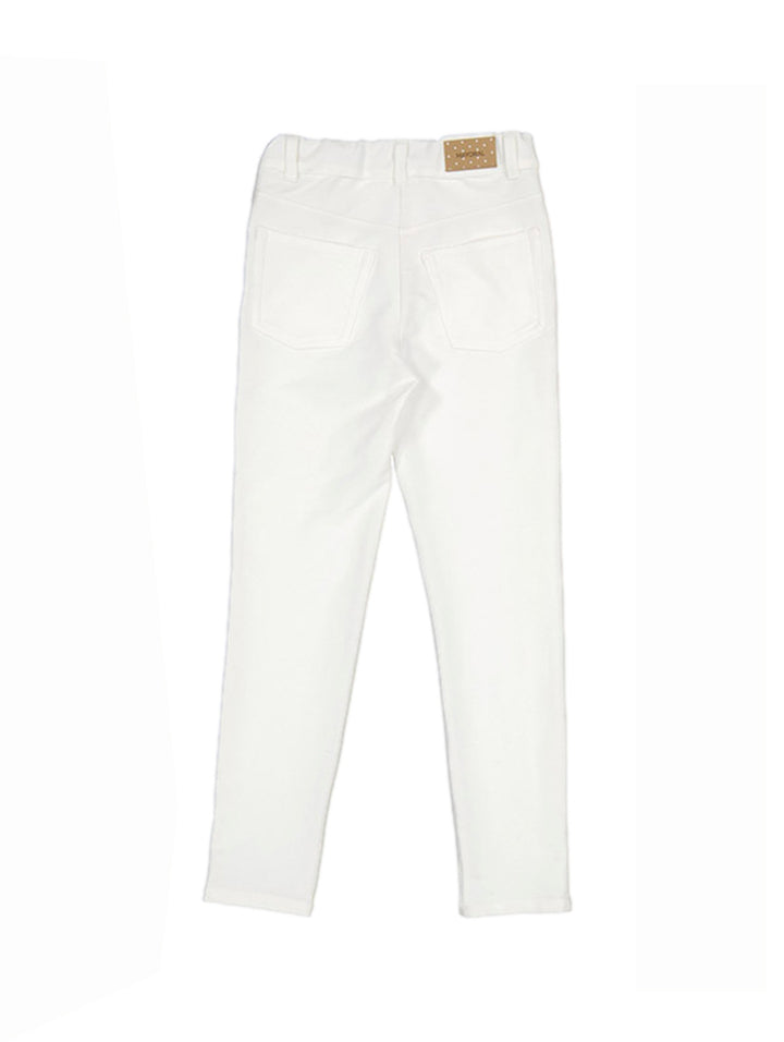 Pantalón color crudo para niña con detalles decorativos laterales.