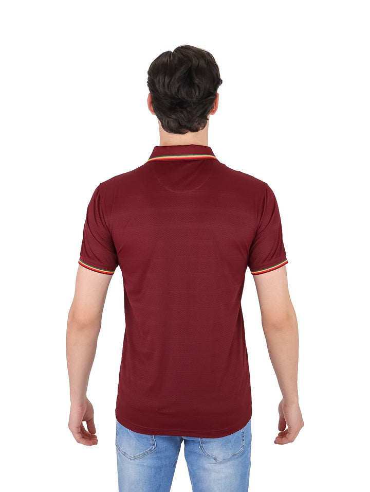 Hombre vistiendo playera polo color burgundy con detalles amarillos en cuello y mangas.