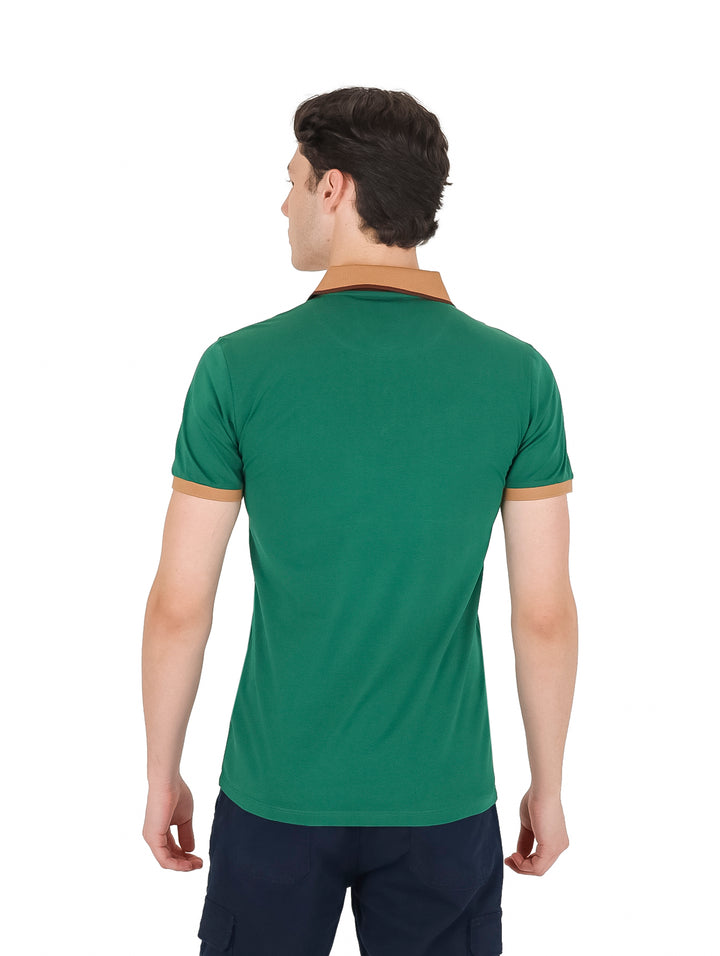 Hombre vistiendo playera polo color verde con detalles en color café en el cuello y bordes de las mangas.