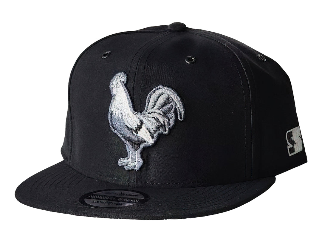 Gorra snapback color negro con un bordado frontal de un gallo blanco y gris.