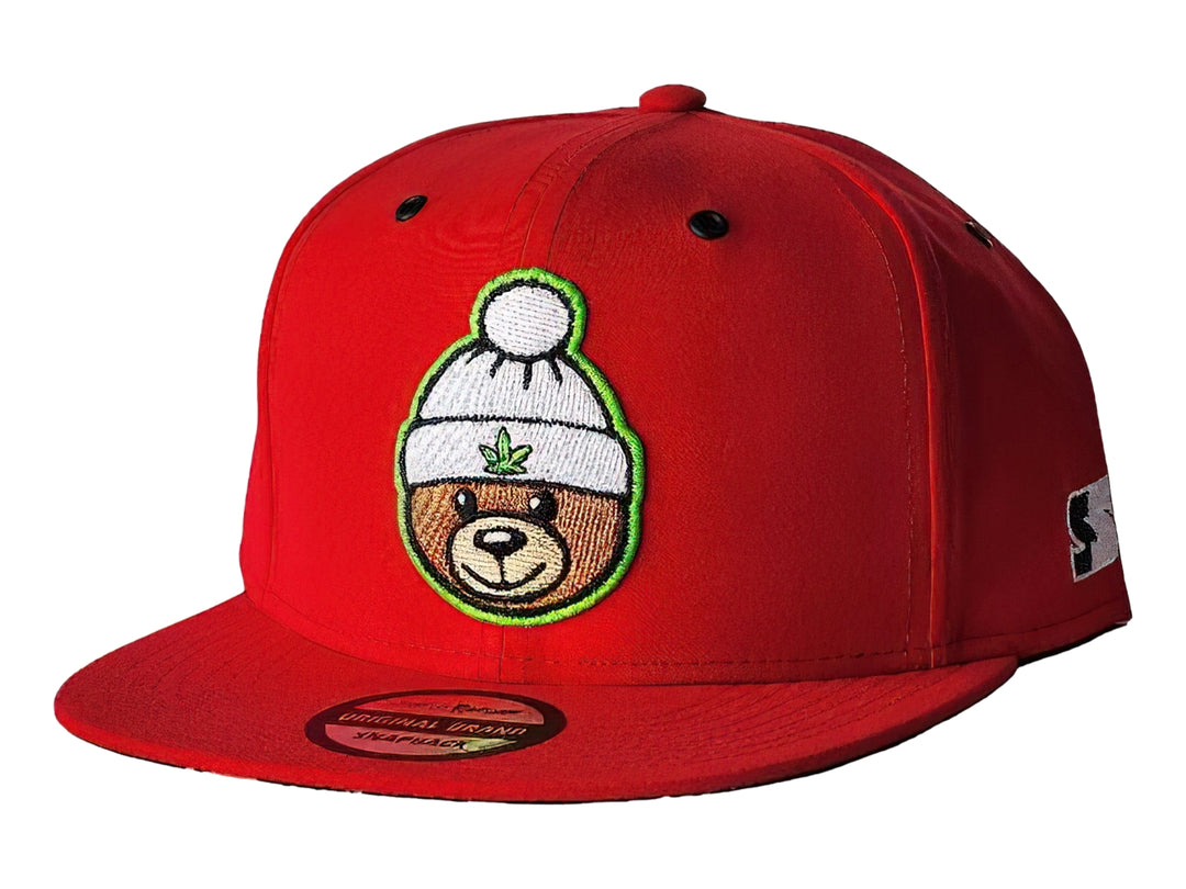 Gorra snapback color rojo con un parche bordado de un oso usando un gorro blanco en el frente.