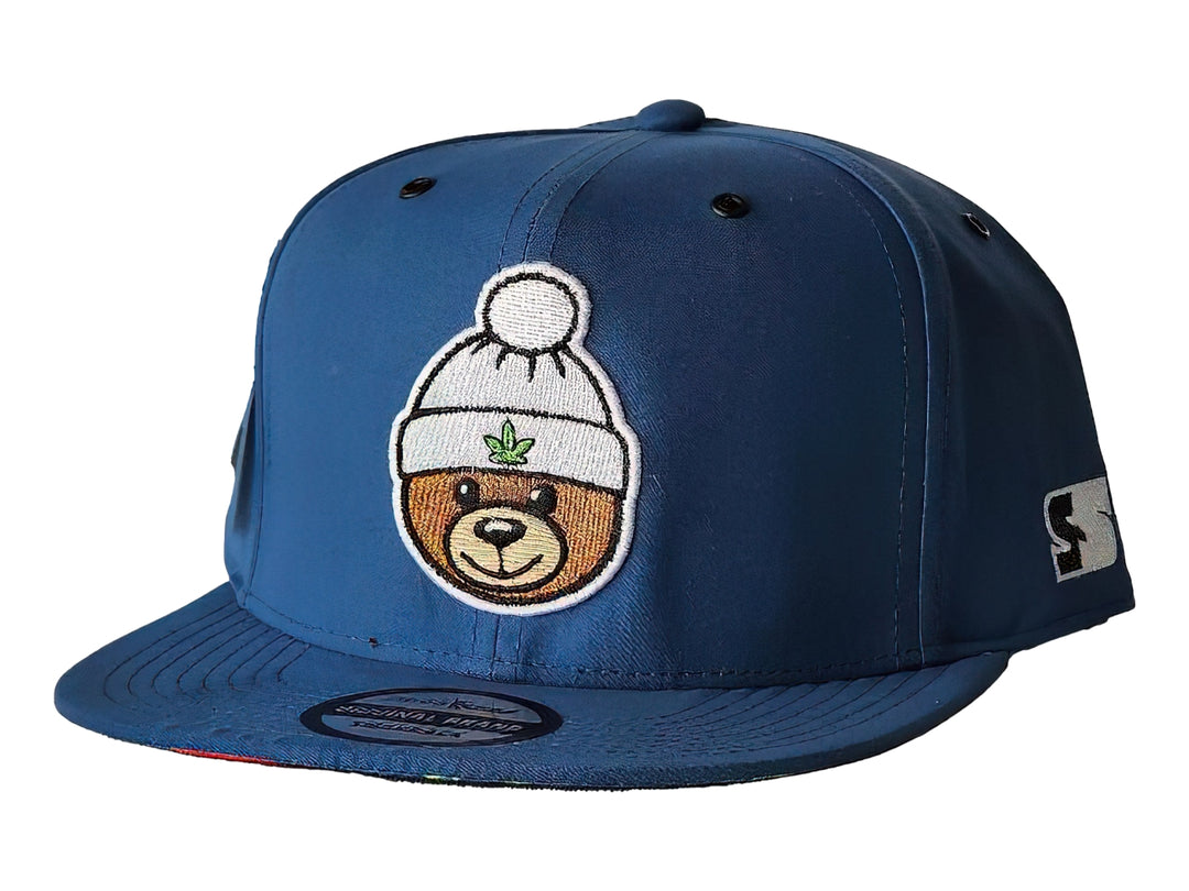 Gorra snapback azul con parche frontal de un oso con gorro blanco y hoja de cannabis.