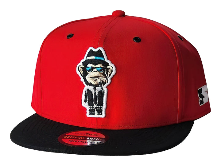 Gorra snapback roja con visera negra y parche frontal de un mono con gafas y sombrero.