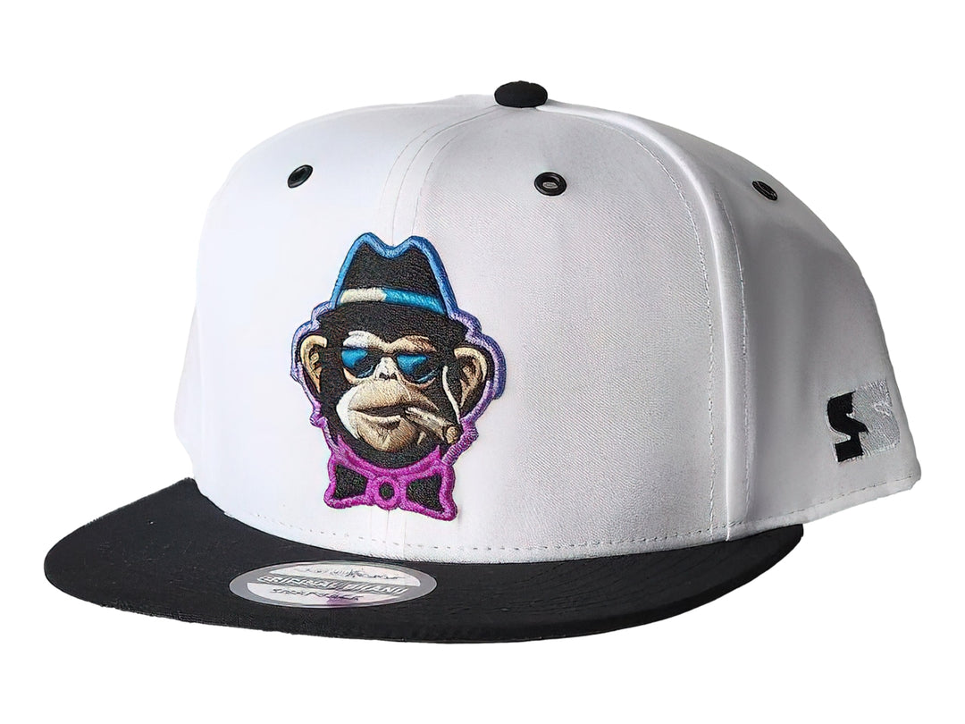 Gorra snapback blanca con visera negra y un parche frontal bordado de un mono con gafas y sombrero.